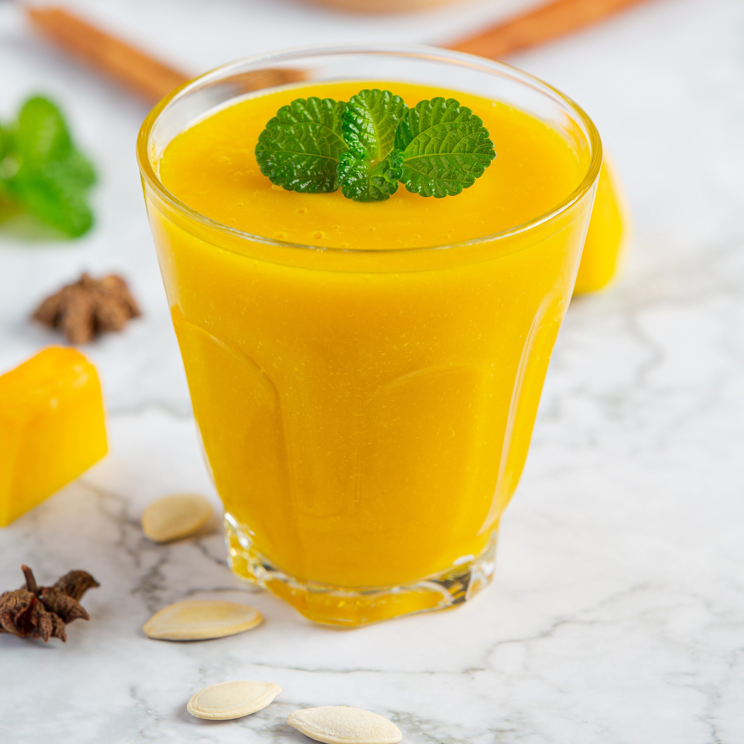 a glass of pumpkin juice place on white marble  floor
